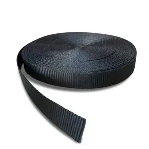 Eine Rolle Gurtband aus schwarzem Nylongewebe liegt auf einem schlichten weißen Untergrund, teilweise ausgerollt, sodass die strukturierte, gerippte Oberfläche sichtbar ist.