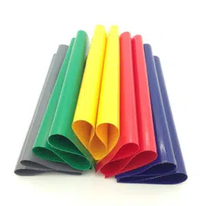 PVC-Planenflicken 680 g/m² in Grau, Grün, Gelb, Rot und Blau werden aufgerollt und aufrecht mit U-förmigen Biegungen angeordnet, um ihre glänzende Textur auf weißem Hintergrund hervorzuheben.