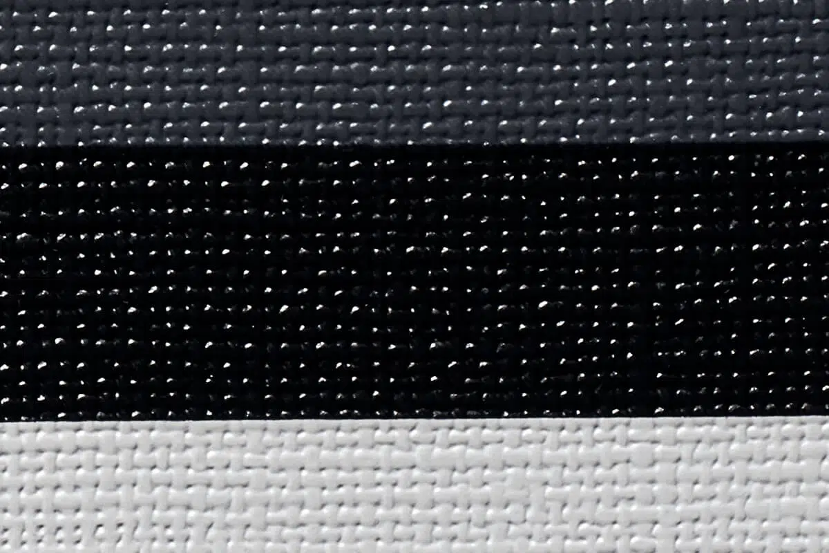 Eine Nahaufnahme des MEHGIES® VALMEX® Solera Vorzeltplane-Stoffes zeigt drei horizontale Streifen: dunkelgrau, schwarz und hellgrau. Das Webmuster verleiht ihm ein subtiles taktiles Aussehen.