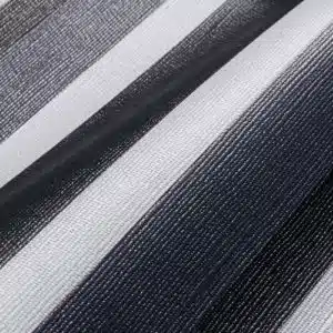 Nahaufnahme des MEHGIES® VALMEX® Solera Vorzeltplane-Stoffes mit vertikalen schwarzen, grauen und weißen Streifen. Die gewebte Textur und die Schattierungen erzeugen einen subtilen Farbverlaufseffekt.