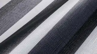 Nahaufnahme des MEHGIES® VALMEX® Solera Vorzeltplane-Stoffes mit vertikalen schwarzen, grauen und weißen Streifen. Die gewebte Textur und die Schattierungen erzeugen einen subtilen Farbverlaufseffekt.