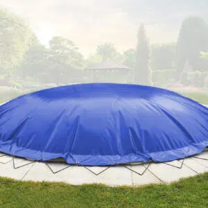 Ein großes rundes Trampolin mit einer Runde aufblasbarem Poolplane steht auf einer Steinterrasse in einem angelegten Garten mit Bäumen und einem Pavillon.