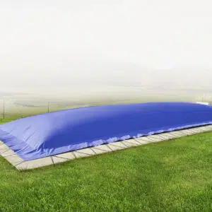 Die rechteckige aufblasbare Poolplane schützt den Pool im grasbewachsenen Garten mit Steinrand inmitten nebliger Landschaft.
