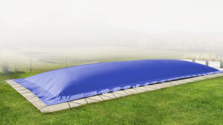 Die rechteckige aufblasbare Poolplane schützt den Pool im grasbewachsenen Garten mit Steinrand inmitten nebliger Landschaft.