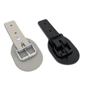Zwei Schnallkappen mit Scheuerunterlage - eine beige mit silberner Schnalle, eine schwarze mit schwarzer Schnalle - liegen auf weißem Grund.