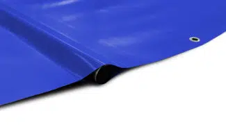 Eine Nahaufnahme der Runde Poolplanen (Stangenabdeckung), einer blauen Plane mit einer Metalltülle in einer Ecke, die auf einer weißen Fläche liegt.