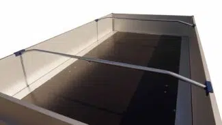 Alubügel für Flachplanen - verstellbar: Metallischer Pritschenanhänger mit hohen Seitenschienen, offenem Dach, dunkler Antirutschoberfläche, blauen Eckbeschlägen und weißen Wänden. Isoliert auf weißem Hintergrund.