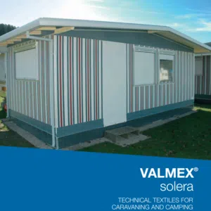 Ein Wohnwagen mit gestreifter Außenseite, zwei Fenstern, flachem Dach und weißer Tür auf grasbewachsenem Gelände. Text: „MUSTER - MEHGIES® VALMEX® solera Vorzeltplane - Technische Textilien für Caravaning und Camping.“.