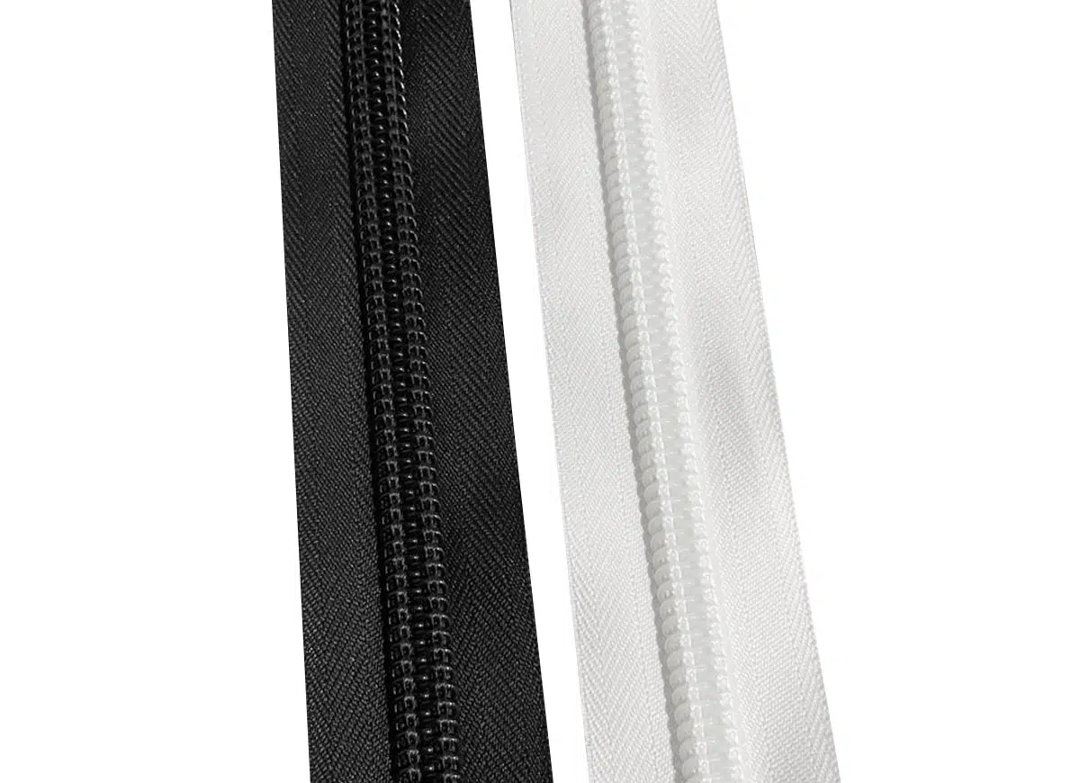 Eine Nahaufnahme von zwei parallelen Reißverschlüssen von YKK vor einem weißen Hintergrund, wobei links ein schwarzer und rechts ein weißer Reißverschluss zu sehen ist. Zähne und Stoffkanten sind deutlich sichtbar.