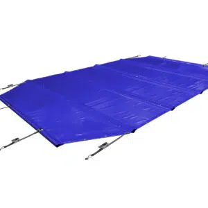 Ein achteckiger Pool ist mit einer durchgehenden blauen, achteckigen Poolplanen (Stangenabdeckung) bedeckt, die mit Seilen befestigt ist. Er ist von Palmen und einem Holzzaun umgeben, alles auf einem hellbraunen Fliesenpflaster.