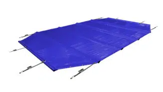 Ein achteckiger Pool ist mit einer durchgehenden blauen, achteckigen Poolplanen (Stangenabdeckung) bedeckt, die mit Seilen befestigt ist. Er ist von Palmen und einem Holzzaun umgeben, alles auf einem hellbraunen Fliesenpflaster.