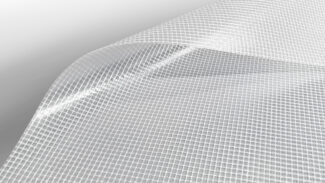 Nahaufnahme eines flexiblen, transparenten Materials mit Gittermuster, leicht gekrümmt wie eine Ebene nach Maß. Die glänzende Oberfläche hebt die Textur hervor, vor einem weißen Hintergrund, der ins Grau übergeht und so für einen minimalistischen Look sorgt.