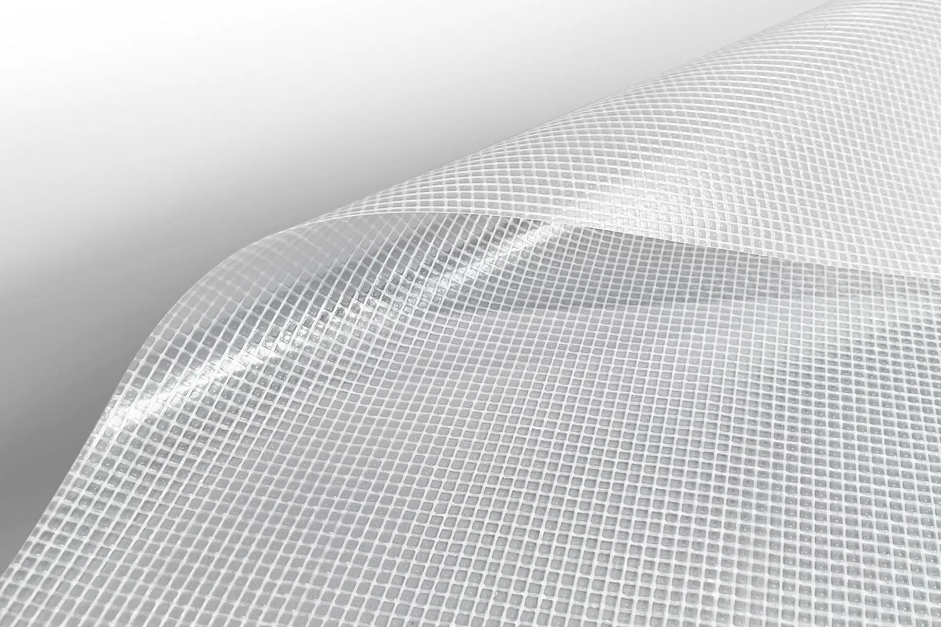 Nahaufnahme einer transparenten Folie mit Gittermuster, wie ein Flugzeug nach Maß, das eine strukturierte Oberfläche erzeugt. Die linke Seite ist vor einem hellgrauen Hintergrund nach oben gewölbt und hebt das exquisite Muster und die Struktur hervor.