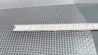 Nahaufnahme eines Maßbandes auf einem gitterförmigen PVC-Netz (550 g/m²) mit kleinen quadratischen Öffnungen. Das 2,18 m breite, hochwertig beschichtete, transluzente PVC-Plane ist mit Maßangaben in Zentimetern abgebildet.