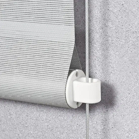 Nahaufnahme eines teilweise ausgerollten grauen Rollos, das auf einer weißen Halterung vor einer strukturierten grauen Wand montiert ist und in seinem modernen Design an elegante Senkrechtmarkisen erinnert.