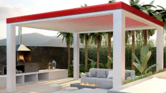 Eine moderne Außenterrasse mit einer weißen Pergola mit rotem Dach, einem bequemen grauen Sofa, einer Feuerstelle und einem eingebauten Grill. Umgeben von üppigem Grün, Palmen und einer malerischen Bergkulisse.