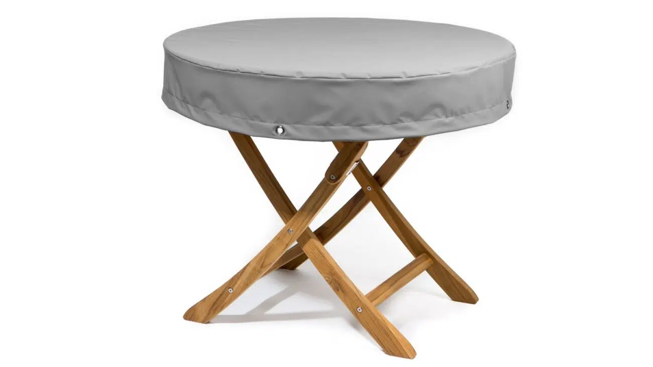 Ein runder, tragbarer Klapptisch aus Holz mit gekreuzten Beinen und einer grauen Tischplattenabdeckung mit der Aufschrift „Tischhaube rund mit 15 cm Überhang (Teak Safe).