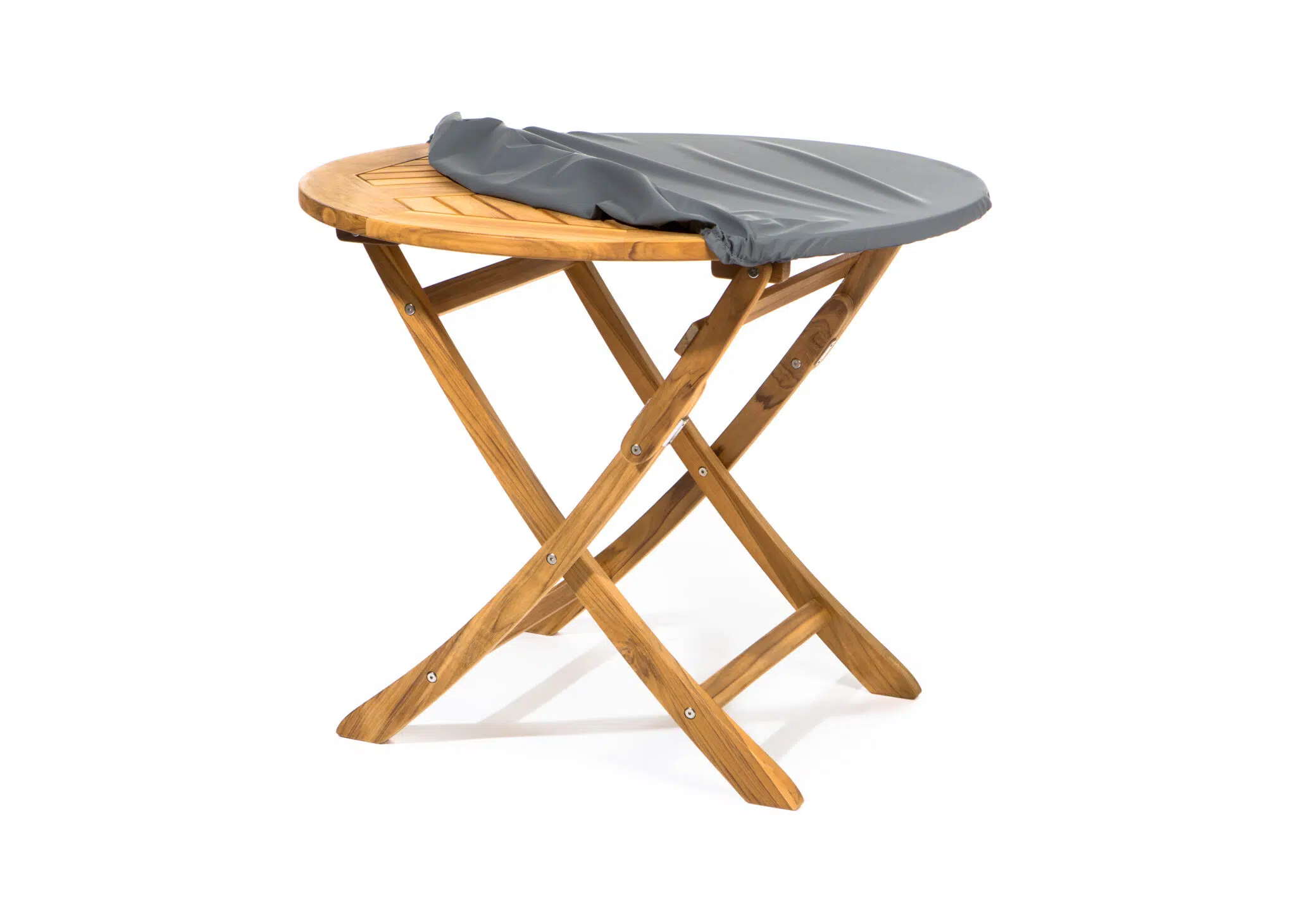 Ein kleiner Klapptisch aus Holz mit gekreuzten Beinen ist teilweise mit einem grauen, drapierten Stoff oder einer grauen Decke bedeckt. Der Tisch steht vor einem schlichten weißen Hintergrund.