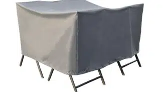 Ein Gartenmöbelset mit einer passenden grauen Schutzhülle. Die Abdeckung hat eine rechteckige Form und passt über Stühle und einen Tisch. An der Unterkante befinden sich Ösen zur Befestigung.