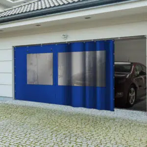 Eine moderne Garage zeigt eine blaue Schiebeplane mit 2x Fenster/ mit 1x Tür (mit Fenster), die teilweise geöffnet ist und in der ein Auto auf einer Kopfsteinpflasterauffahrt steht.