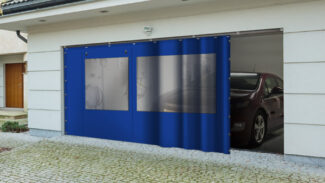 Eine moderne Garage zeigt eine blaue Schiebeplane mit 2x Fenster/ mit 1x Tür (mit Fenster), die teilweise geöffnet ist und in der ein Auto auf einer Kopfsteinpflasterauffahrt steht.