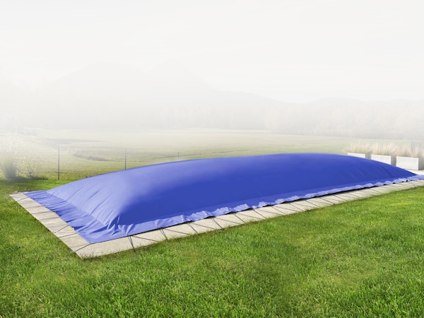 Die rechteckige aufblasbare Poolplane schützt den Pool im grasbewachsenen Garten mit Steinrand inmitten nebliger Landschaft.