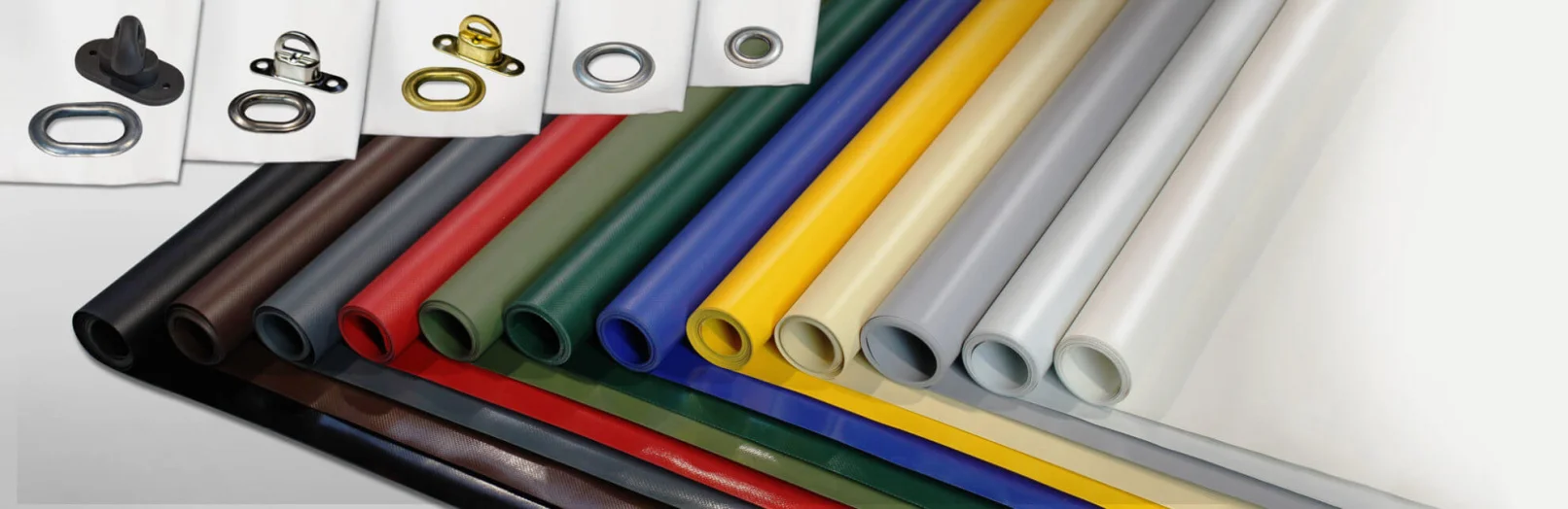 Es werden verschiedene farbige Planenstoffe in Rollenform ausgestellt, die in vielen Farben wie Schwarz, Braun, Rot, Grün, Blau, Gelb, Grau und Weiß erhältlich sind. Oben links sind Metallösen und Planenzubehör zu sehen.
